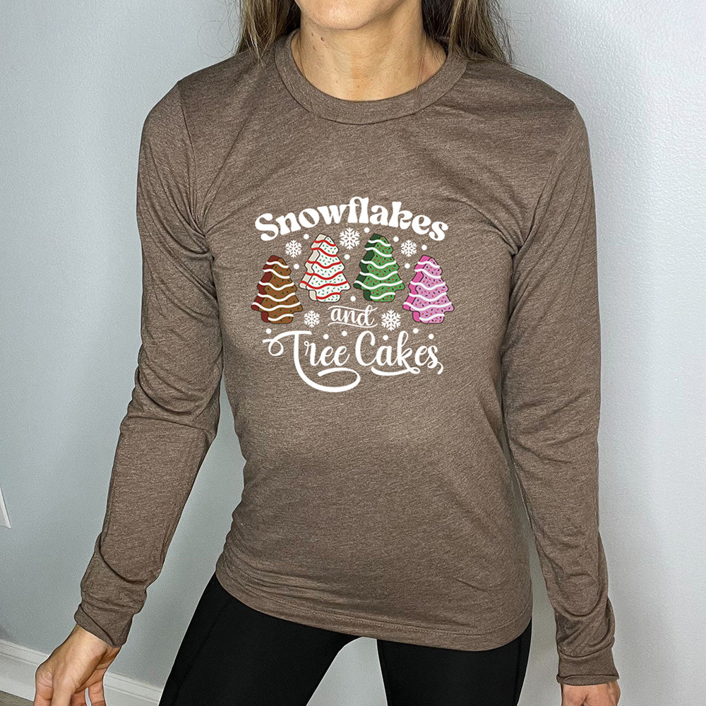 heather brown long sleeve shirt with the words "Snowflakes & Tree Cakes" on it and graphics matching those words