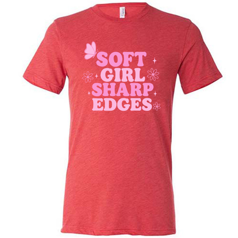 red unisex tee with the words "soft girl sharp edges" in all caps, with graphics of a few little flowers and stars and one butterfly