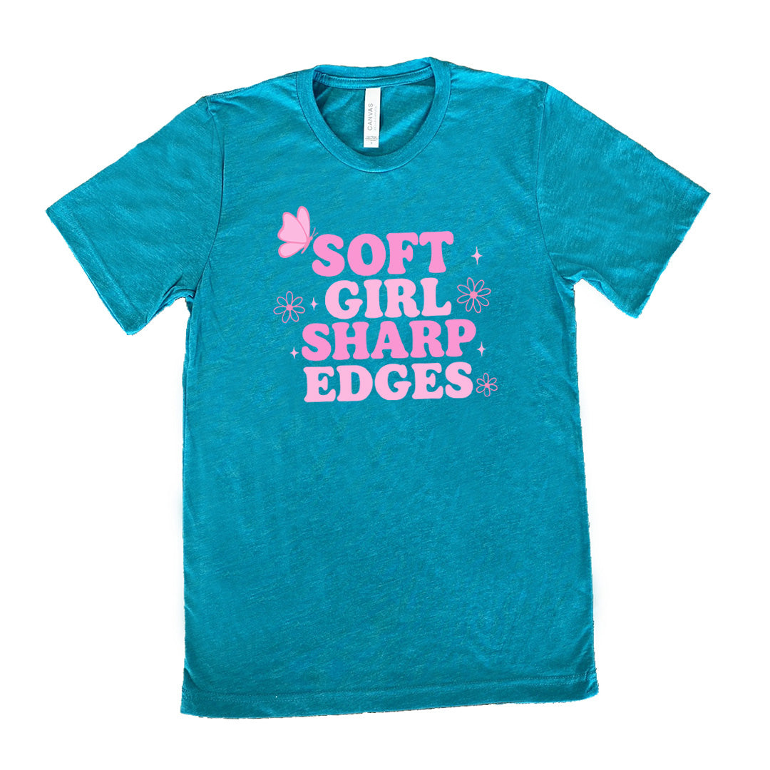 teal unisex tee with the words "soft girl sharp edges" in all caps, with graphics of a few little flowers and stars and one butterfly