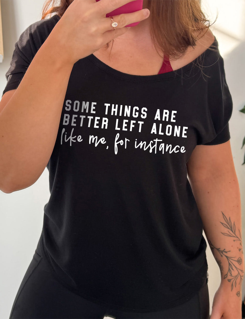 black slouchy tee with the words on it saying "some things are better left alone" and then in different font underneath saying "like me, for instance"