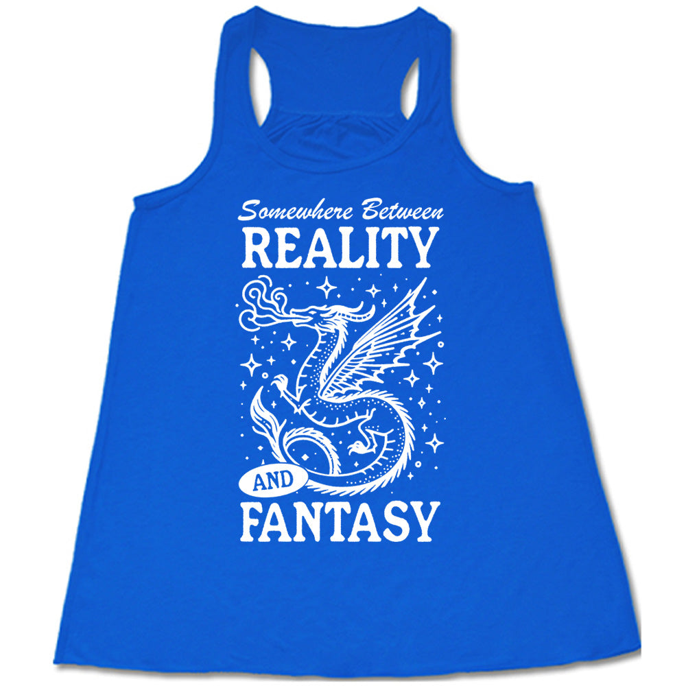 blue racerback flowy tank with the words "somewhere between reality and fantasy" on it, around the graphic of a dragon among stars, breathing fire