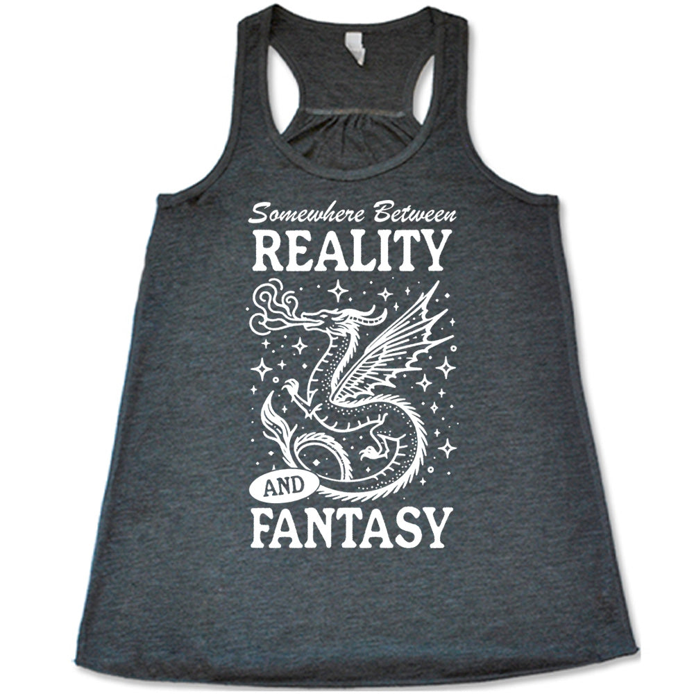 grey racerback flowy tank with the words "somewhere between reality and fantasy" on it, around the graphic of a dragon among stars, breathing fire