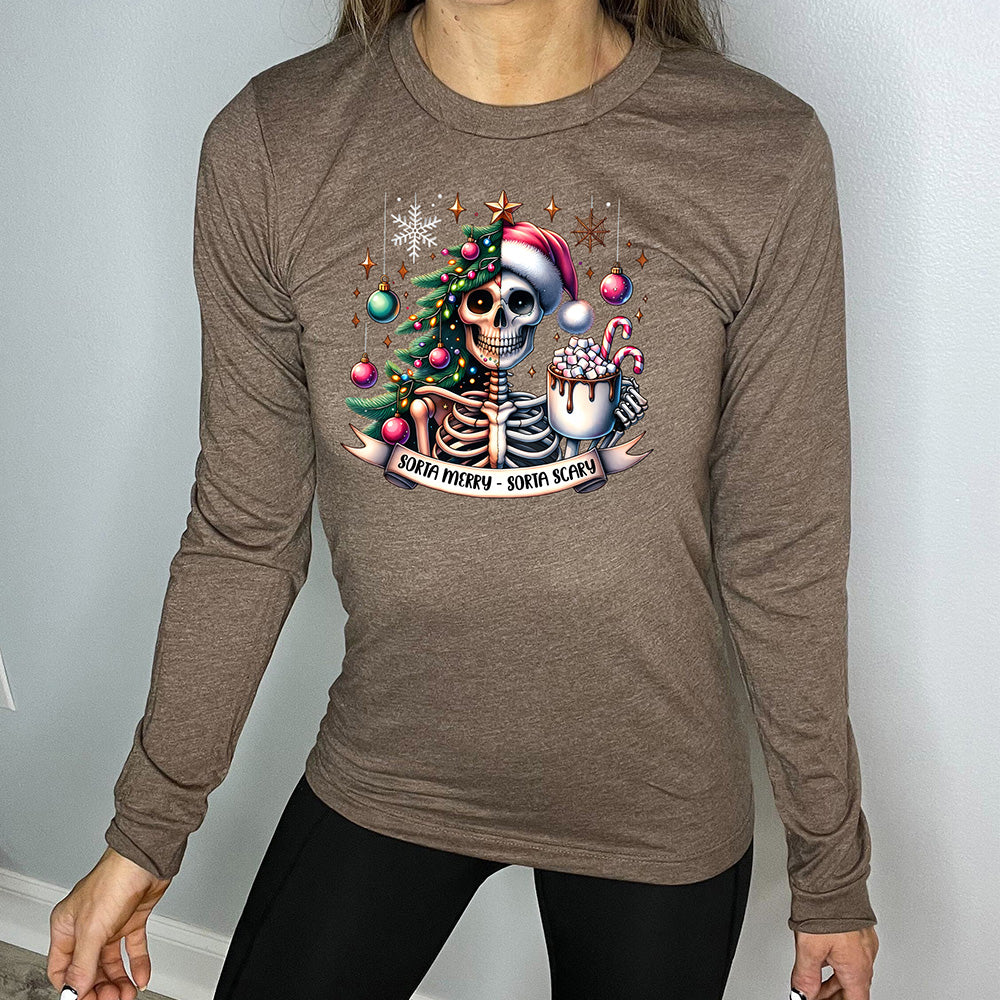 heather brown long sleeve shirt with the words "Sorta merry - sorta scary" on it, below the graphic of a skeleton with half its body mixed with a Christmas tree and ornaments and a snowflake, and other half with a Santa hat on, holding a mug piled high with marshmallows and a candy cane ,and some more ornaments