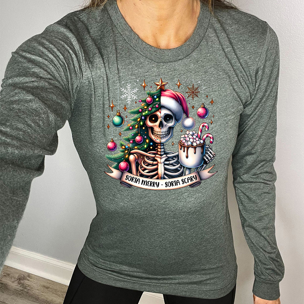heather forest long sleeve shirt with the words "Sorta merry - sorta scary" on it, below the graphic of a skeleton with half its body mixed with a Christmas tree and ornaments and a snowflake, and other half with a Santa hat on, holding a mug piled high with marshmallows and a candy cane ,and some more ornaments