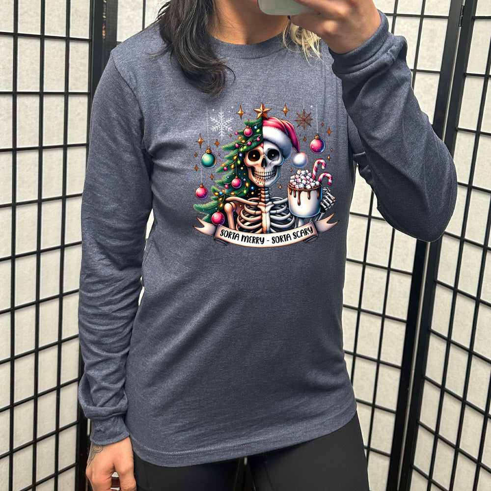 heather navy long sleeve shirt with the words "Sorta merry - sorta scary" on it, below the graphic of a skeleton with half its body mixed with a Christmas tree and ornaments and a snowflake, and other half with a Santa hat on, holding a mug piled high with marshmallows and a candy cane ,and some more ornaments