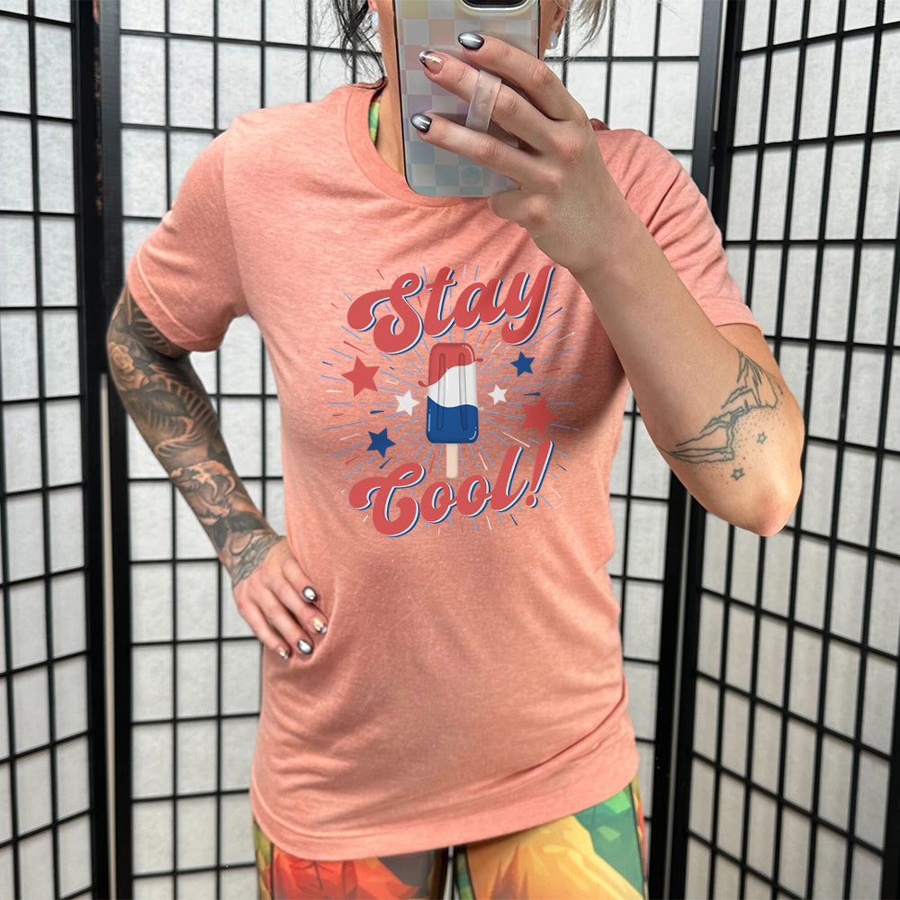 Model wearing sunset colored shirt with a red white and blue popsicle graphic on it that says "Stay Cool!"