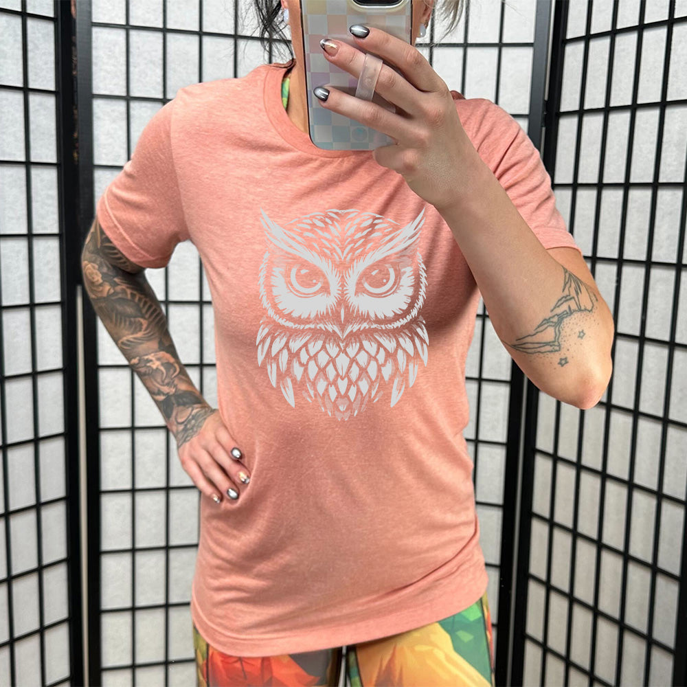 Model wearing sunset colored shirt with stylized owl graphic on it