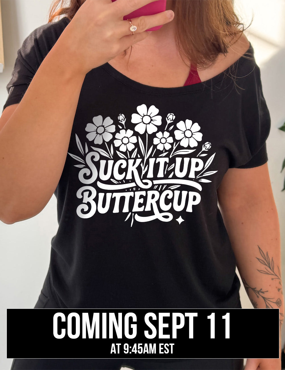 black slouchy tee with the words "suck it up buttercup" on it, with the graphic of a bouquet of flowers, the words in front of the stems coming September 11th