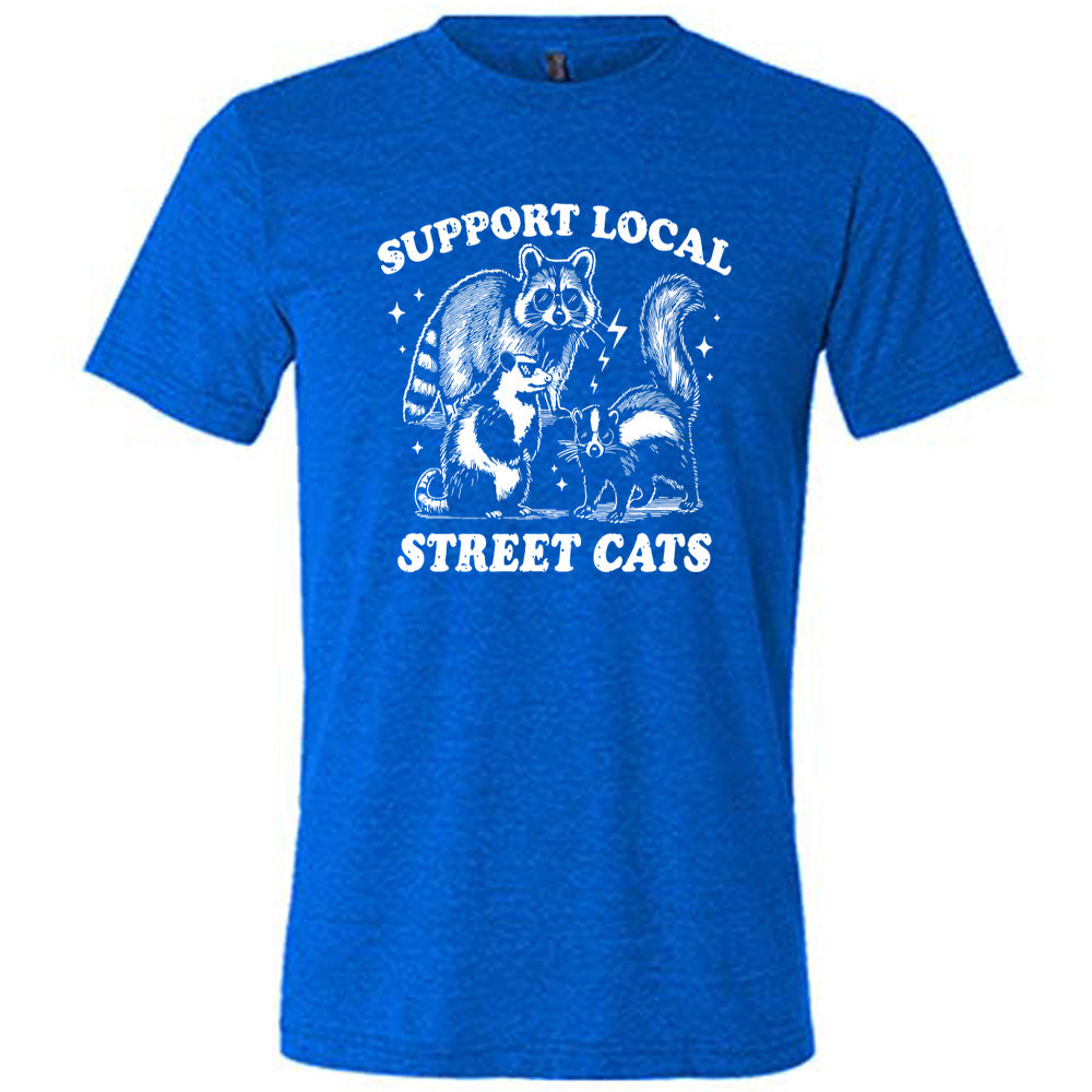 blue unisex tee with the words "support local street cats" and the graphics of a racoon, a skunk, and a possum, all wearing sunglasses, with a few little stars and lightening bolts around