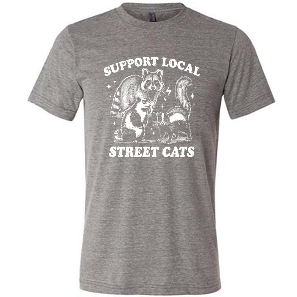 gray unisex tee with the words "support local street cats" and the graphics of a racoon, a skunk, and a possum, all wearing sunglasses, with a few little stars and lightening bolts around