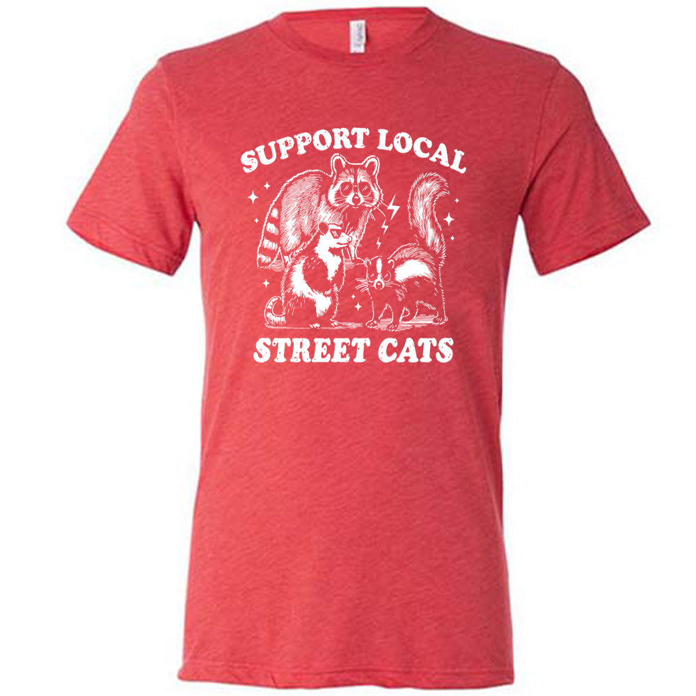 red unisex tee with the words "support local street cats" and the graphics of a racoon, a skunk, and a possum, all wearing sunglasses, with a few little stars and lightening bolts around