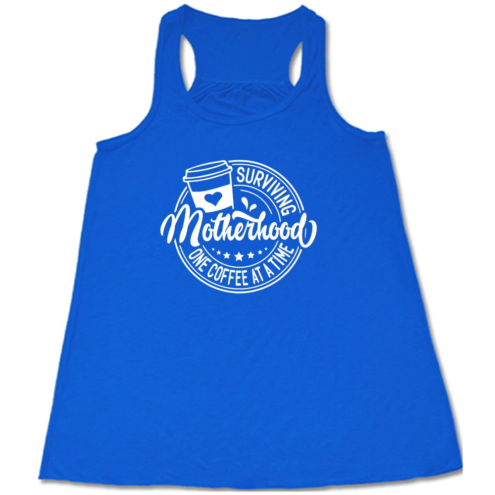 Blue colored flowy tank with a coffee cup graphic on it that says "Surviving Motherhood One Coffee at a Time"