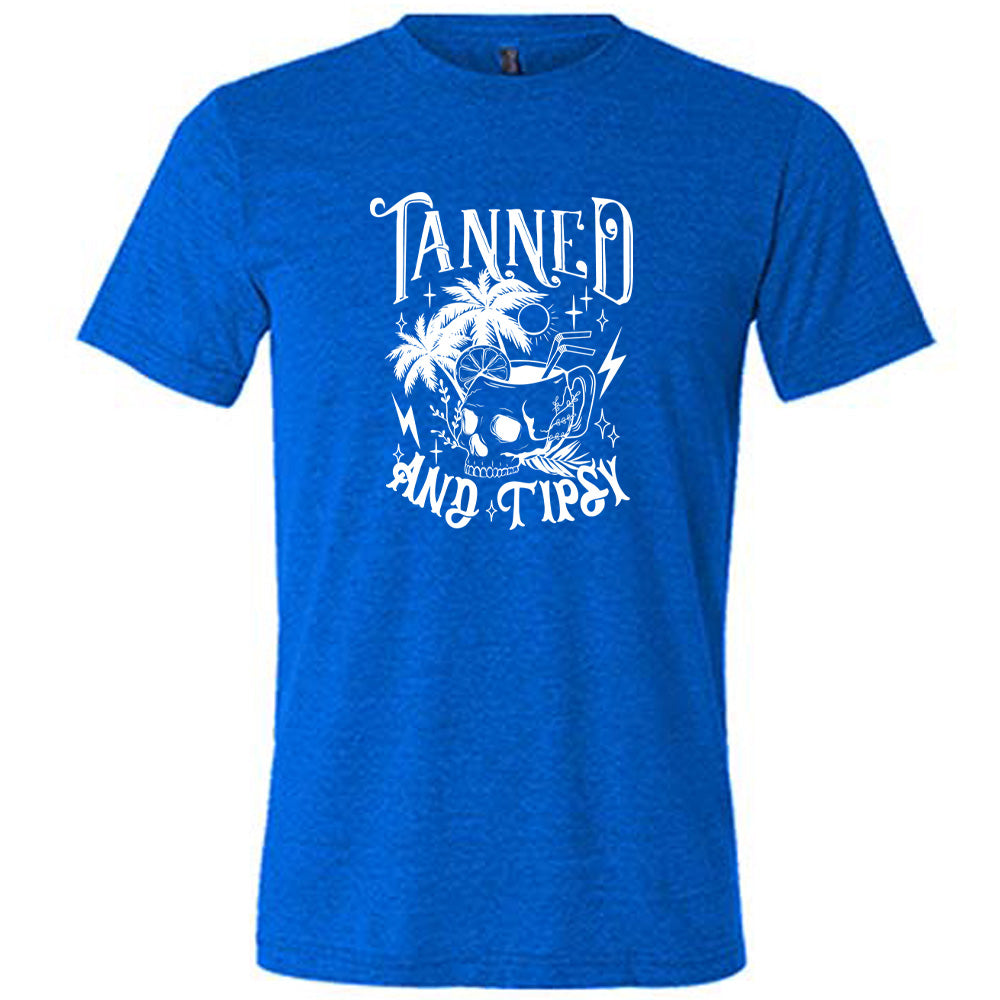 Blue colored shirt with a drink inside a skull cup graphic on it that says "Tanned and Tipsy"