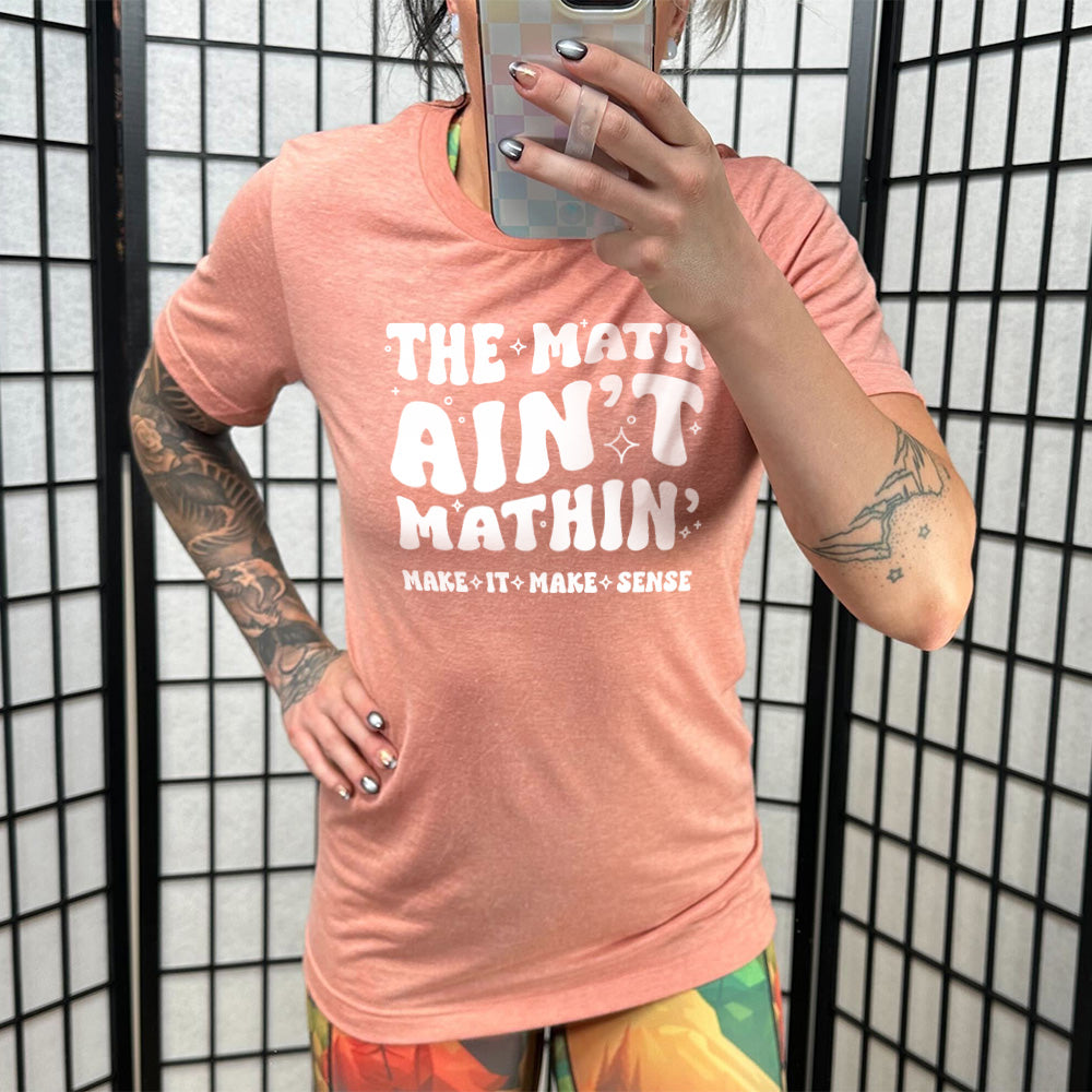 Model wearing sunset colored shirt with graphic on it that says "The Math Ain't Mathin' Make It Make Sense"
