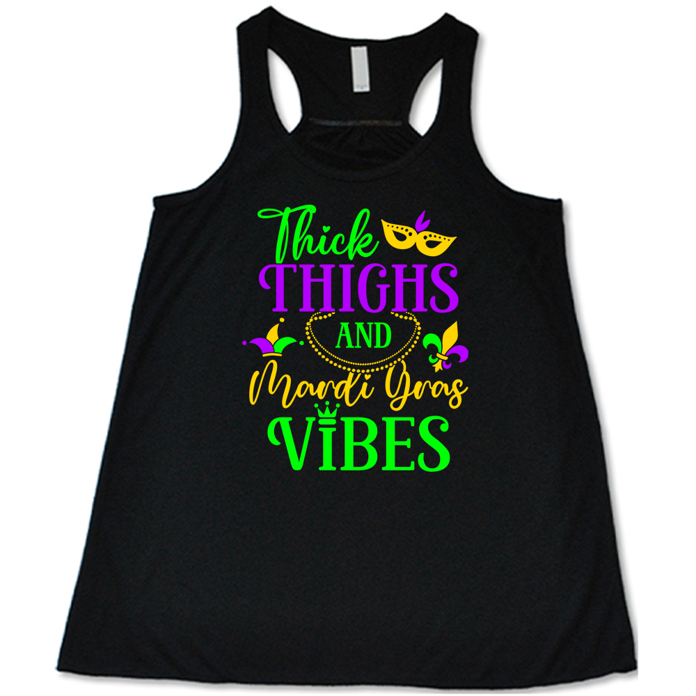 black flowy tank with the words "thick thighs and mardi gras vibes" on it in varying font, with small graphics of mardi gras beads, fleur de lis, a joker hat and a mask
