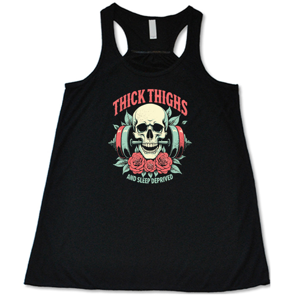 Black colored flowy tank with a skull, flowers, and barbell graphic on it that says "Thick Thighs And Sleep Deprived"