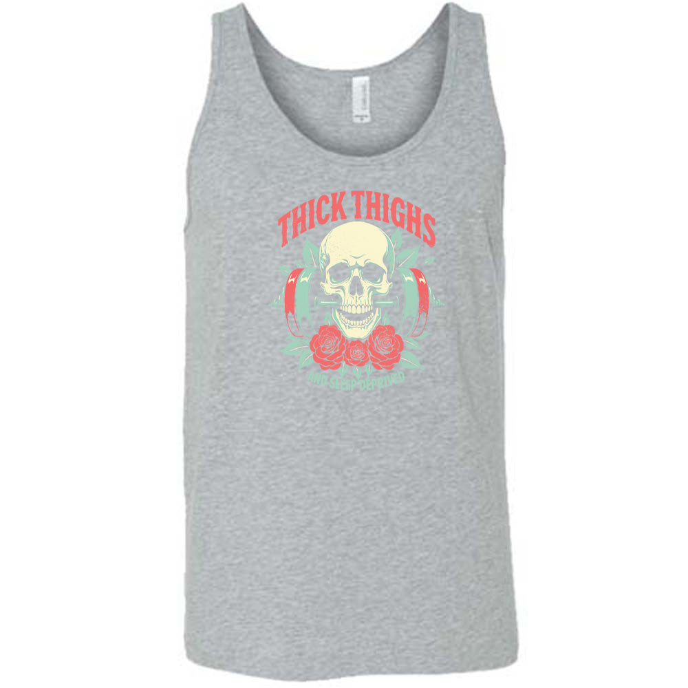 Grey colored tank with a skull, flowers, and barbell graphic on it that says "Thick Thighs And Sleep Deprived"