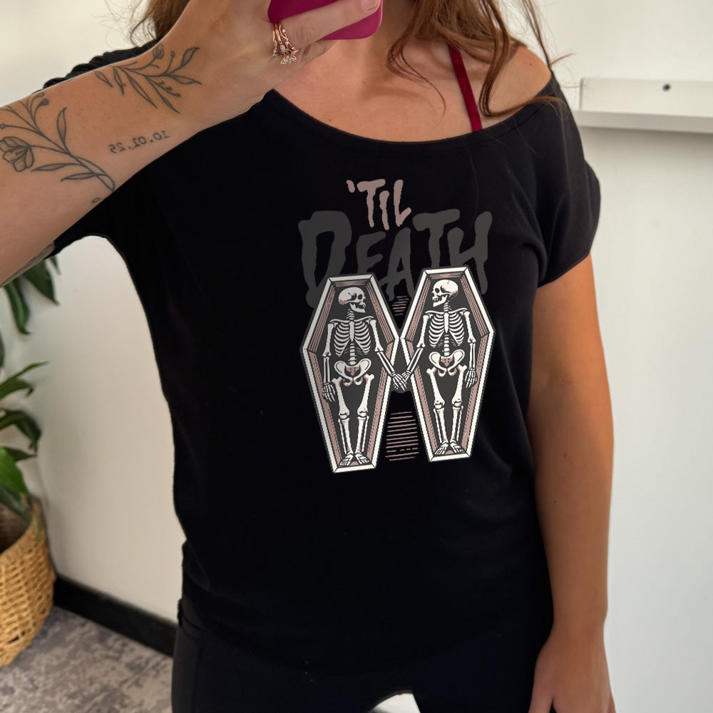 black slouchy shirt with the words "'til death" on it, with graphics of two skeletons, both in their own coffins, holding hands in the middle