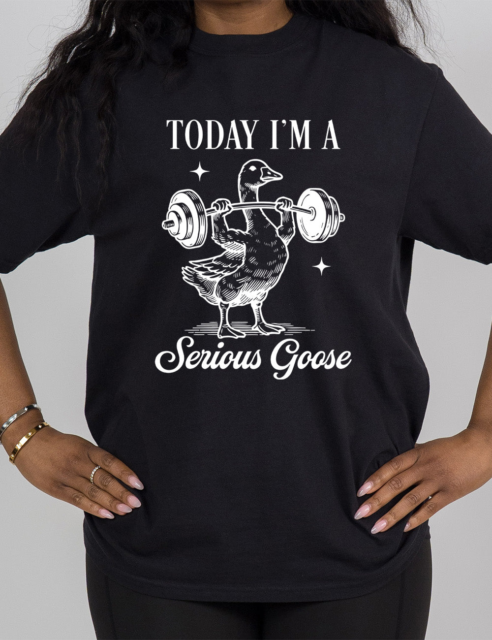 black modern tee with the graphic of a goose lifting a barbell (with arms), and the words around this image saying "today I'm a serious goose"