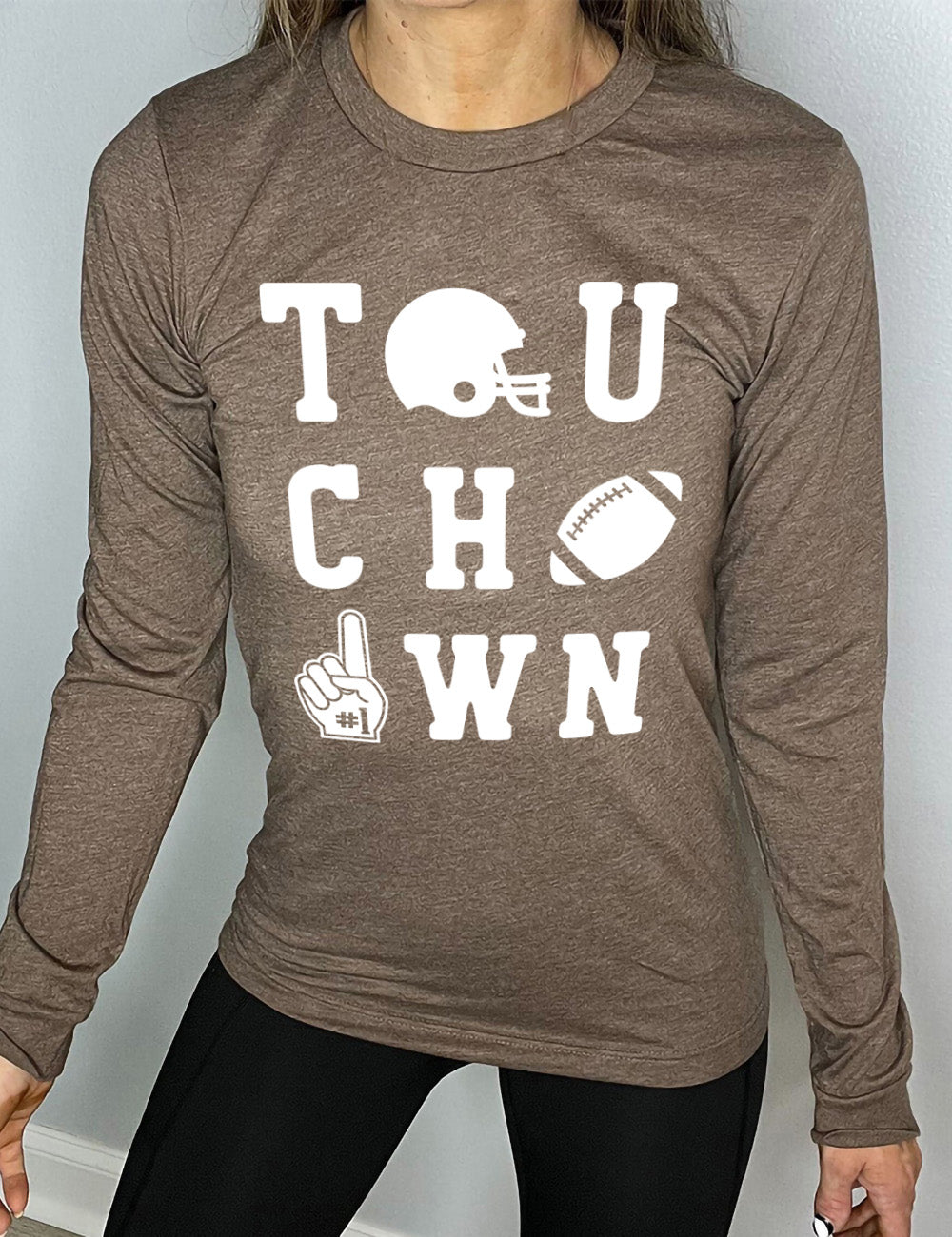 heather brown long sleeve tee with the word "touchdown" spelled out over three rows, and with the first "o" being a football helmet, the "d" being a football, and the last "o" being a foam finger with #1 on it