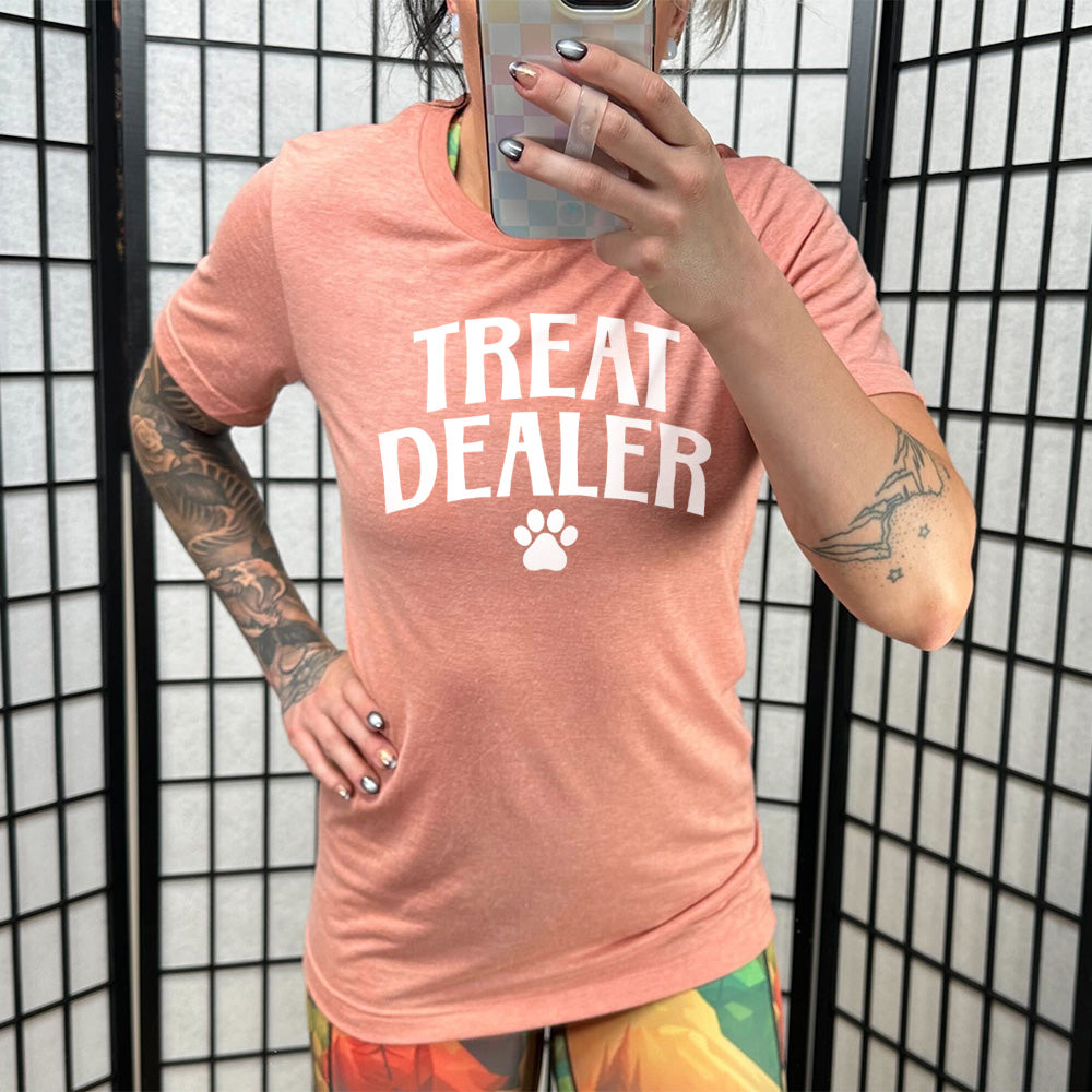 Model wearing sunset colored shirt with paw print graphic on it that says "TREAT DEALER"