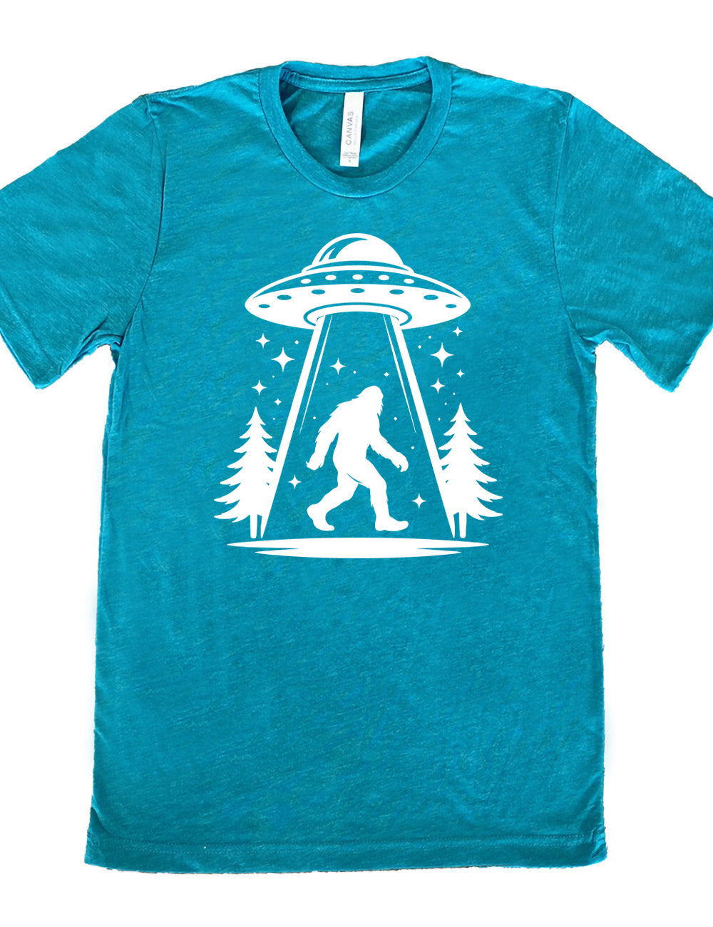 teal unisex tee with the graphic of an alien spaceship beaming bigfoot up, with stars surrounding, and couple pine trees