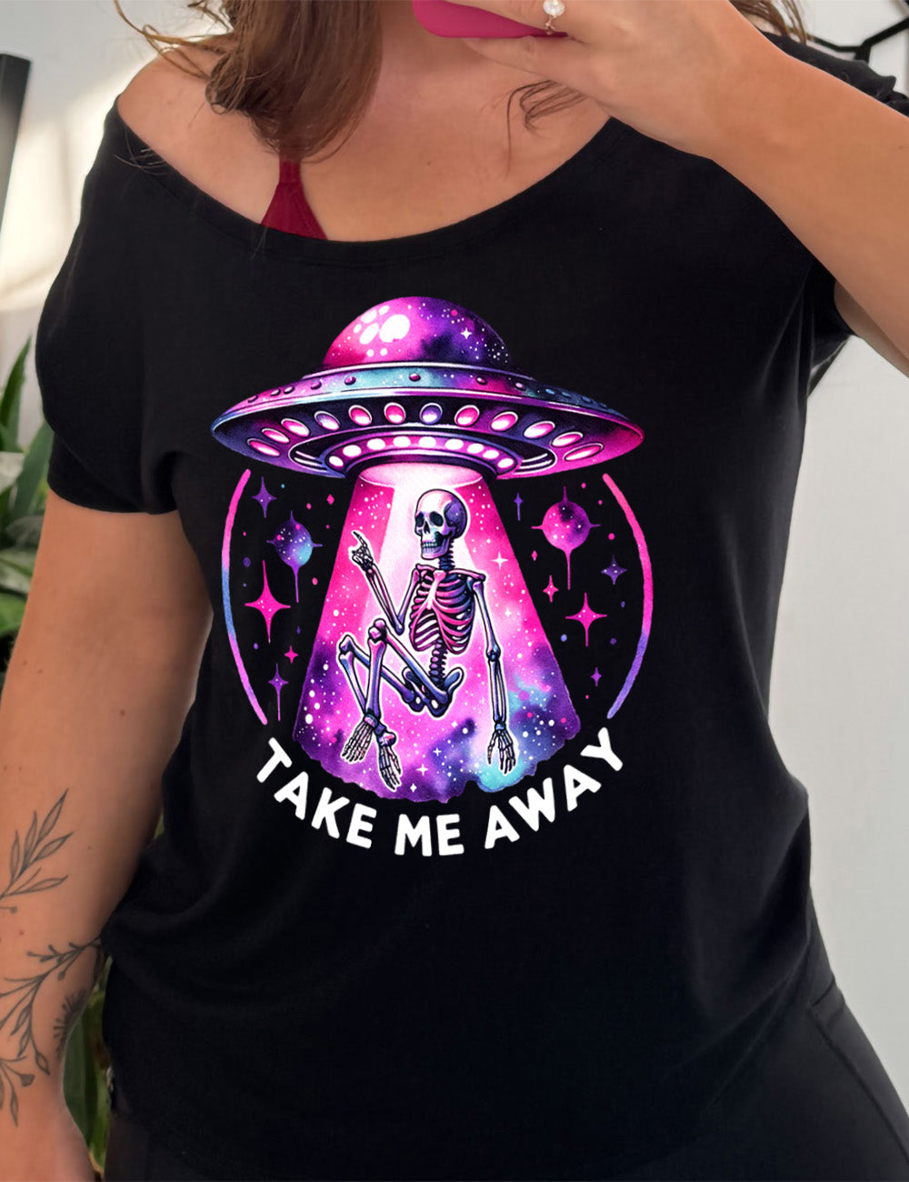 black slouchy tee with the colorful and detailed graphic of an alien spaceship, above little planets and stars, beaming up a skeleton, and the words underneath saying "take me away"