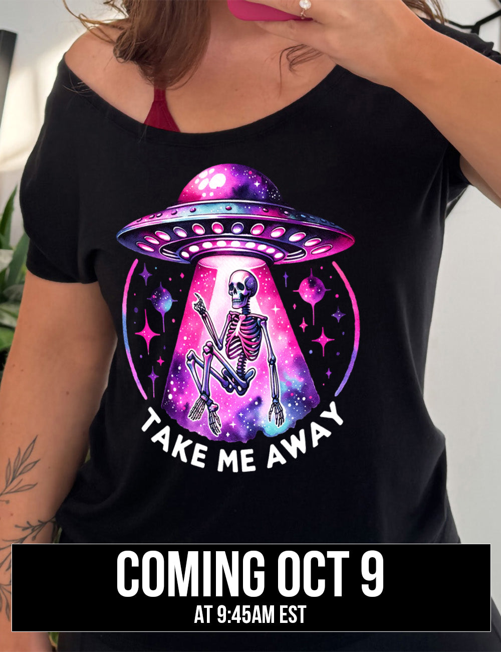 black slouchy tee with the colorful and detailed graphic of an alien spaceship, above little planets and stars, beaming up a skeleton, and the words underneath saying "take me away" Coming October 9th
