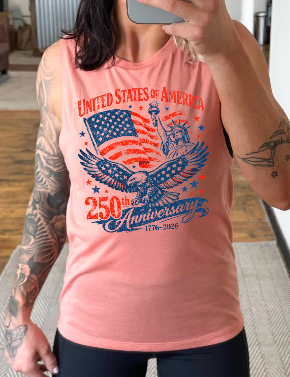 peach muscle tank with the graphic of the eagle, wings spread, the statue of liberty, and an American flag, and lots of little stars, and the words saying "United Stated of America 250th Anniversary 1776-2026"