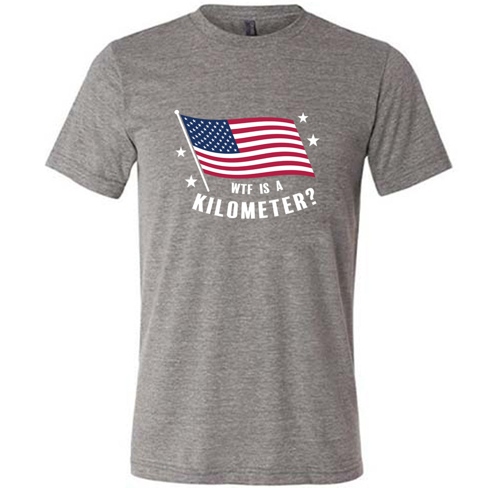 Grey colored shirt with an American flag graphic on it that says "WTF Is A Kilometer?"
