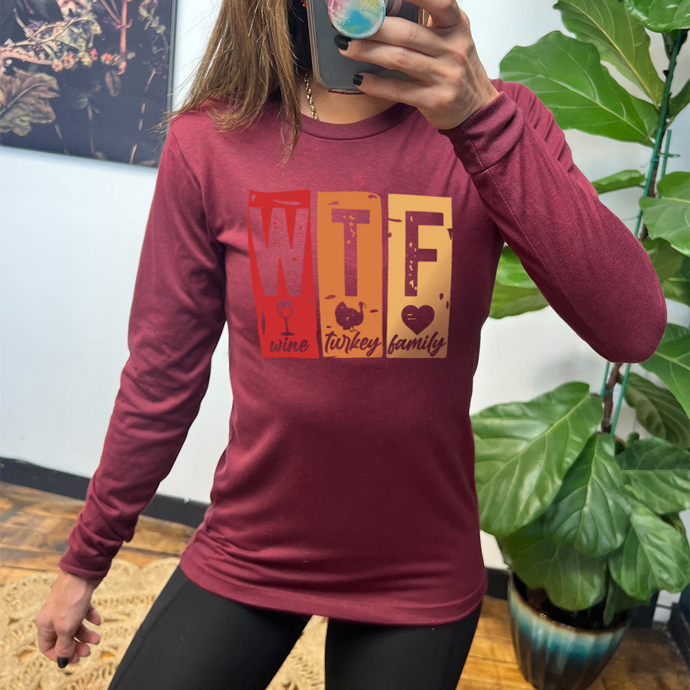heather cardinal long sleeve shirt with a graphic on it that says "WTF" and under the "W" there's a graphic of a wine glass and the word "wine"; under "T" there's a graphic of a turkey and the word "turkey"; under F there's a graphic of a heart and the word "family"