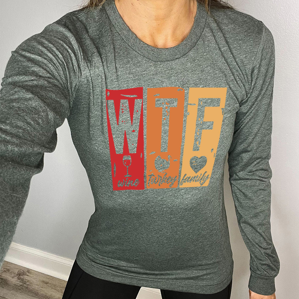 heather forest long sleeve shirt with a graphic on it that says "WTF" and under the "W" there's a graphic of a wine glass and the word "wine"; under "T" there's a graphic of a turkey and the word "turkey"; under F there's a graphic of a heart and the word "family"