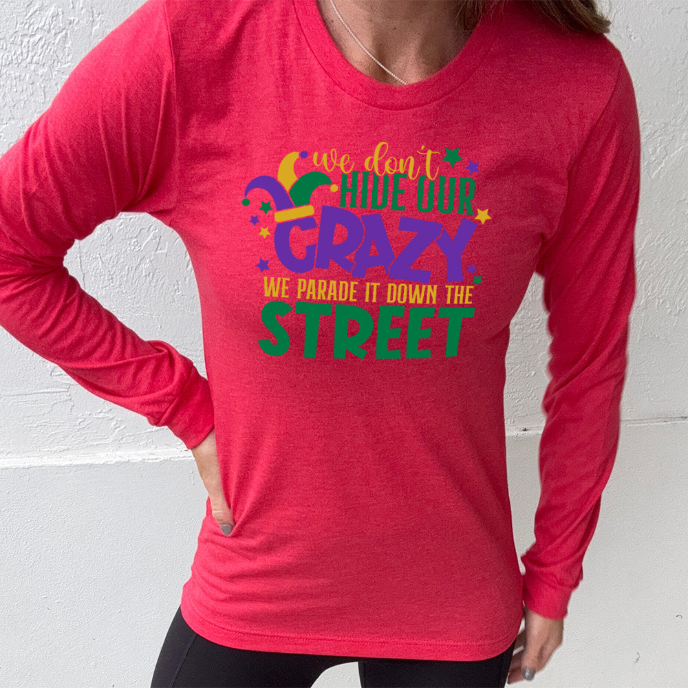 heather red long sleeve tee with the words "we don't hide our crazy we parade it down the street" on it with a joker hat on the letter "c" and a few little stars scattered around