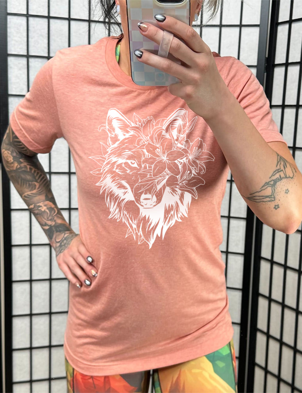 sunset unisex tee with the large graphic of a wolf's head, with lilies covering half of the face, and growing behind its head too