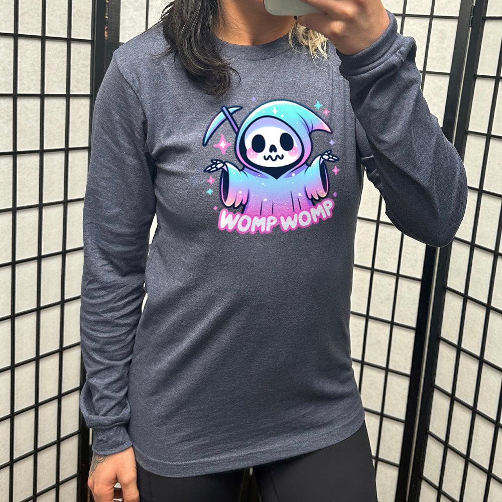 heather navy long sleeve shirt with the text "Womp Womp" on it, with the cartoon graphic of a sparkly-robed grim reaper, skeletal hands raised in question, surrounded by sparkly little stars