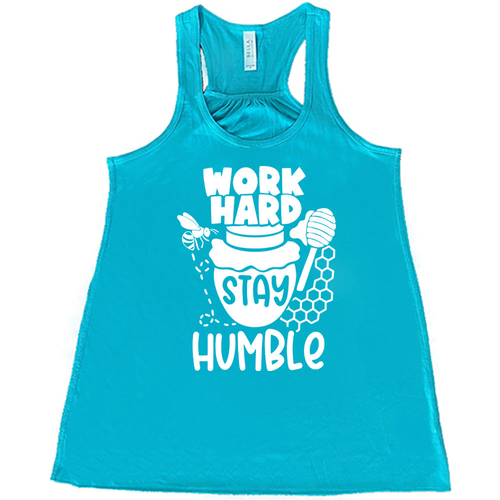 teal flowy racerback tank with the words "work hard stay humble" on it, with the word "stay" on the graphic of a honeypot, and a bee flying around the pot's left, and some honeycomb and a honey spoon on its right