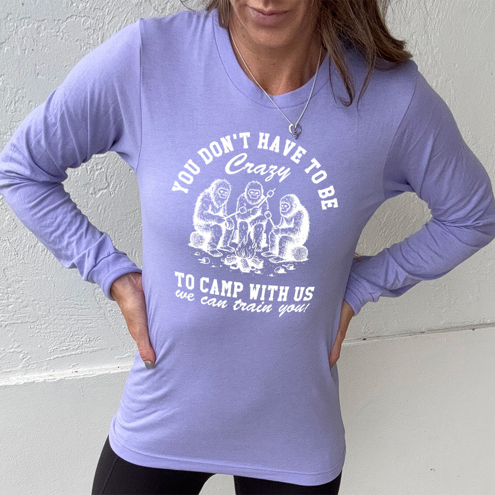 heather dark lavender long sleeve with the words "you don't have to be crazy to camp with us we can train you!" on it with the graphic of three sasquatches toasting marshmallows over a campfire