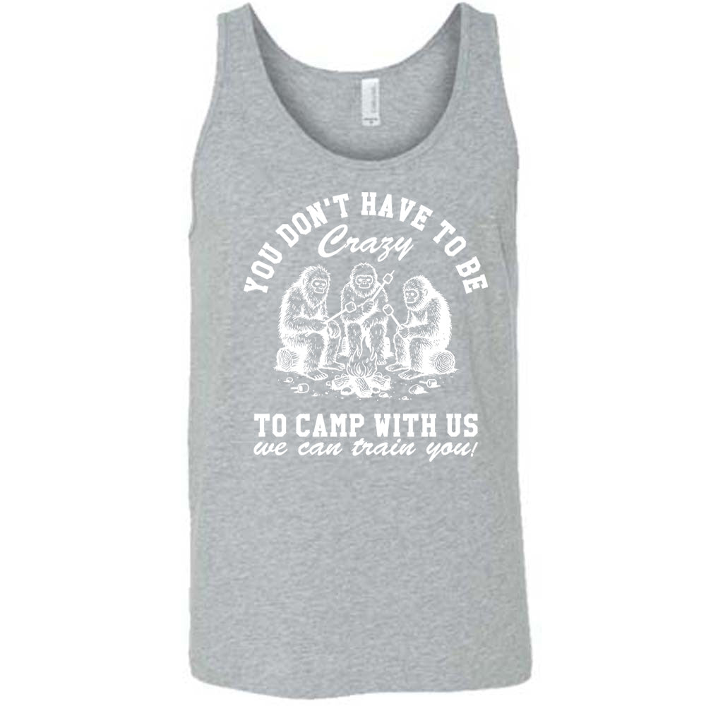 grey unisex tank with the words "you don't have to be crazy to camp with us we can train you!" on it with the graphic of three sasquatches toasting marshmallows over a campfire