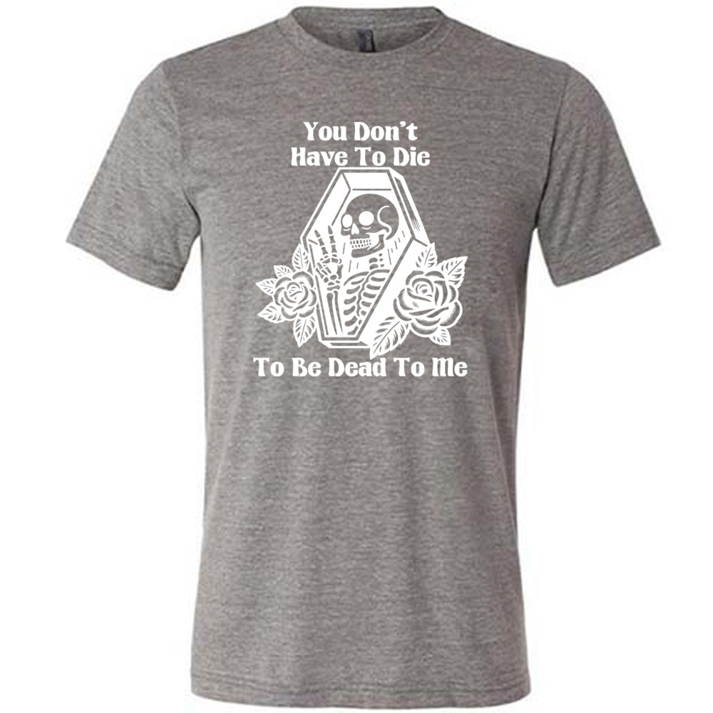 grey unisex tee with the words "You don't have to die to be dead to me" on it with the graphic of a a skeleton in a coffin, giving the peace sign, with two flowers on either side of the coffin