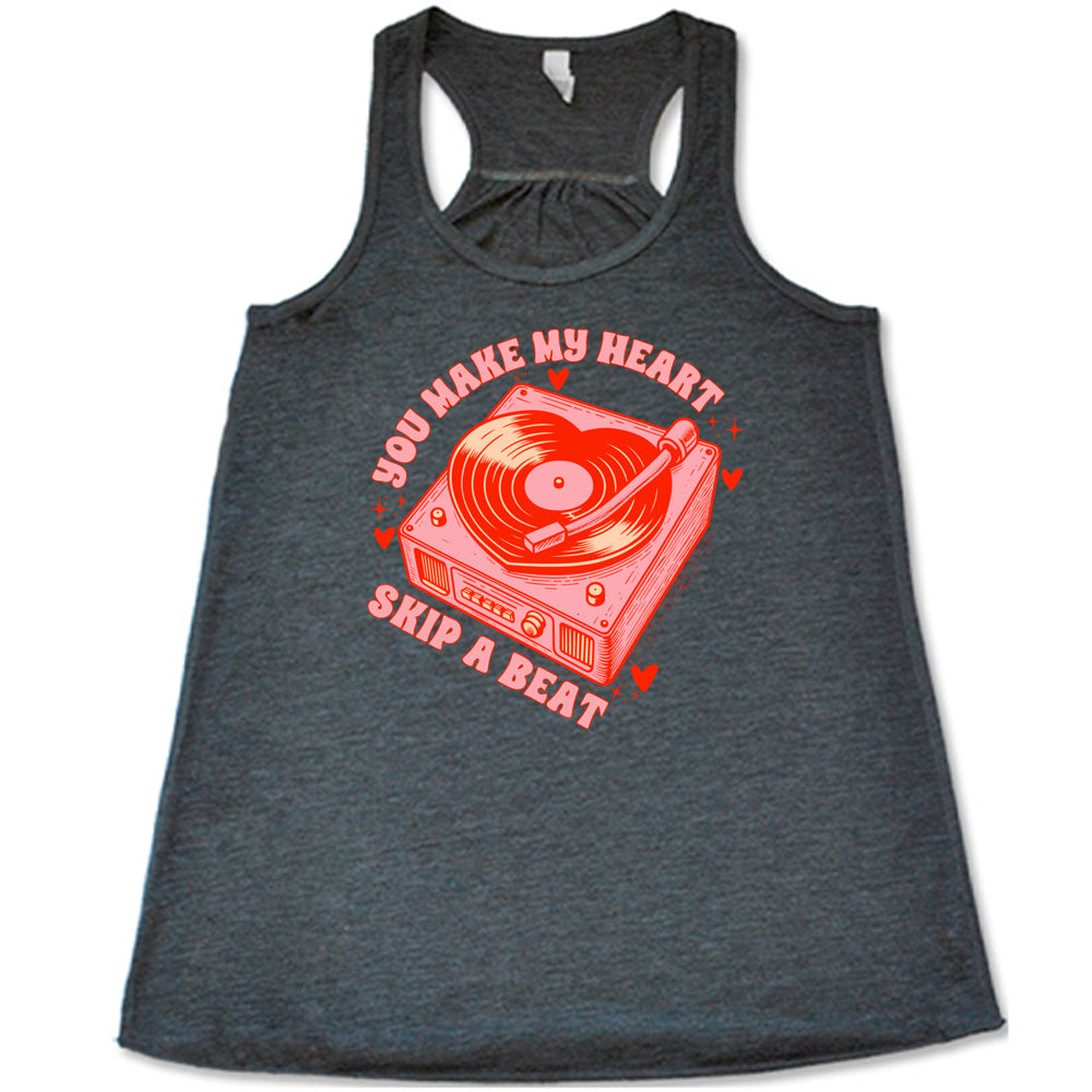 grey flowy shirt with the words "you make my heart skip a beat" on it, with the graphics of a record player, with a record shaped like a heart, with a little hearts and stars around each corner of the player