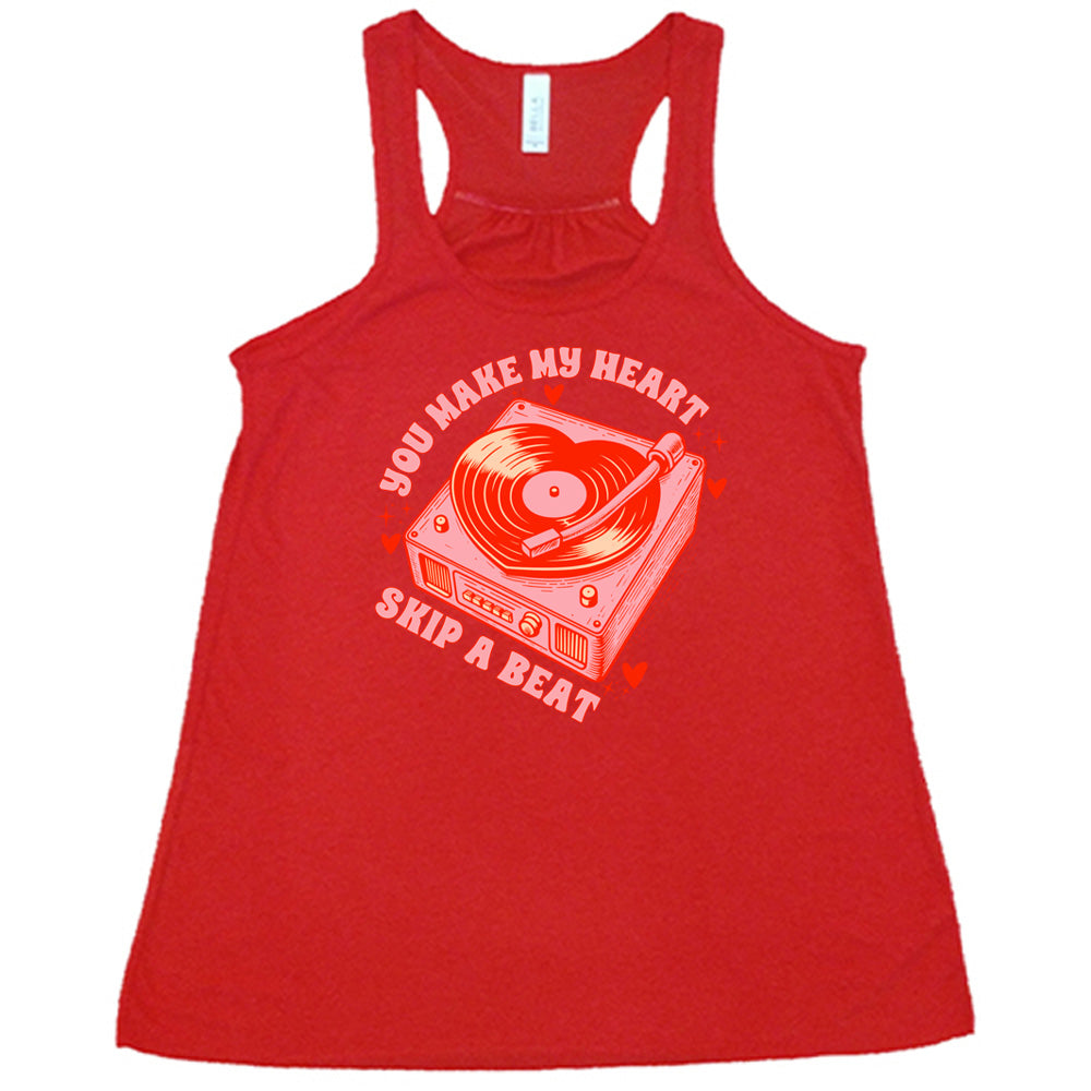 red flowy shirt with the words "you make my heart skip a beat" on it, with the graphics of a record player, with a record shaped like a heart, with a little hearts and stars around each corner of the player