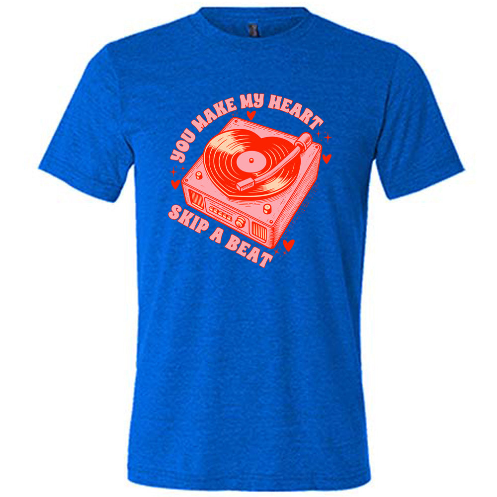 blue unisex tee with the words "you make my heart skip a beat" on it, with the graphics of a record player, with a record shaped like a heart, with a little hearts and stars around each corner of the player