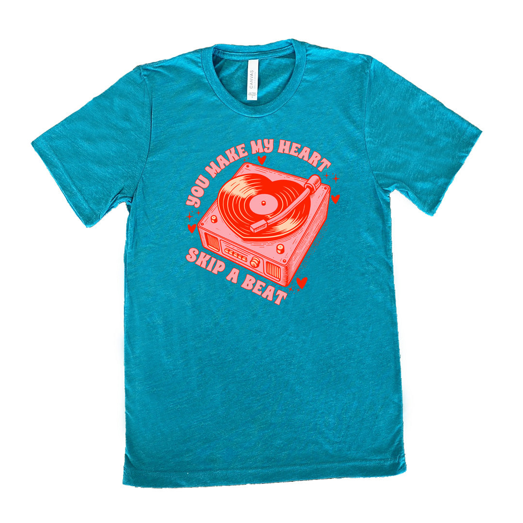 teal unisex tee with the words "you make my heart skip a beat" on it, with the graphics of a record player, with a record shaped like a heart, with a little hearts and stars around each corner of the player