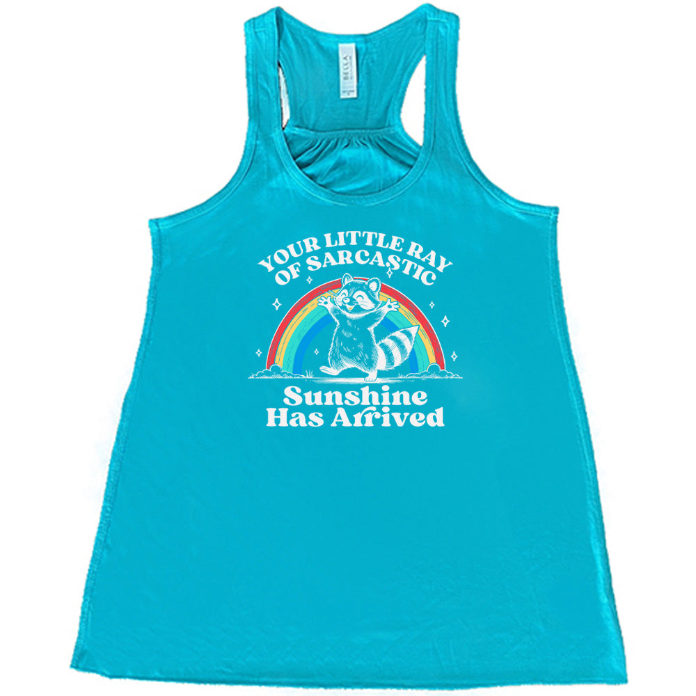 Teal colored flowy tank with a rainbow and raccoon graphic on it that says "Your Little Ray of Sarcastic Sunshine Has Arrived"