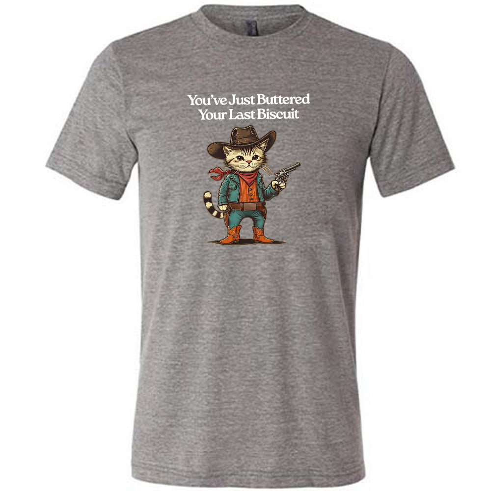 Grey colored shirt with a cowboy cat graphic on it that says "You've Just Buttered Your Last Biscuit"