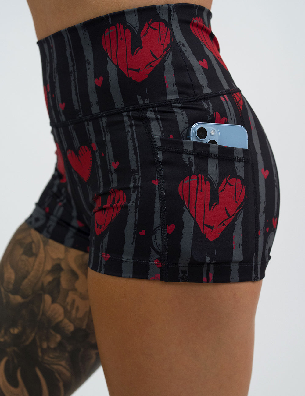 close up of the 2.5 inch red hearts against stripes shorts with a phone in its pocket