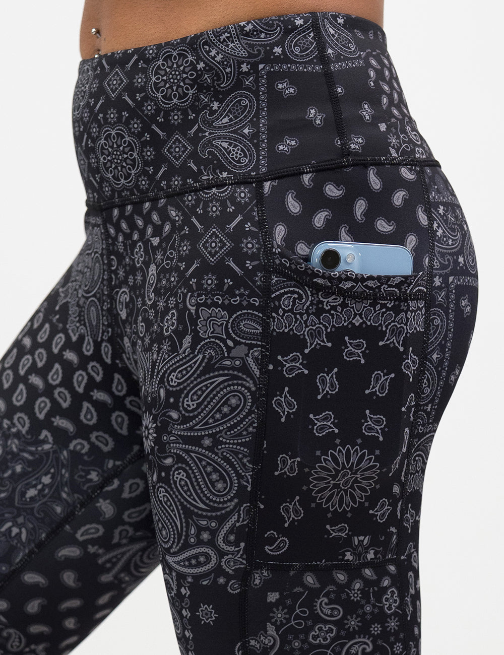close up of the black paisley patterned leggings with a phone in its pocket