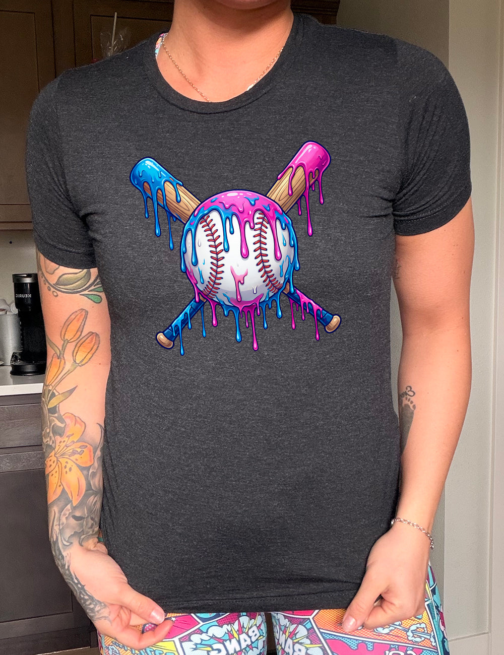 black unisex tee with the graphic of a baseball with two bats crossed behind it, and all of it dripping with blue and pink