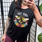 model wearing a black slouchy shirt that says "bee kind" with a bee and flower graphic on it