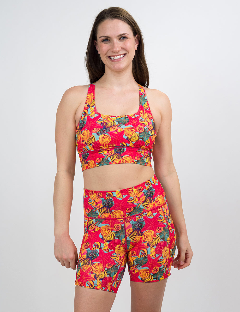 model wearing the 5 inch red starfish with a yellow and blue shell background shorts against a white background